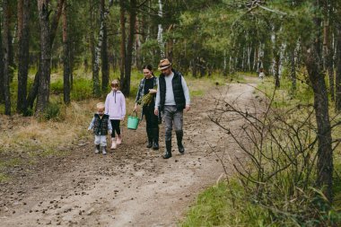 Mutlu bir aile ormanda yürüyüş yapıyor, böğürtlen ve otlar topluyor, patika boyunca seyahat ediyor ve anne ve baba ile çocukları taşlıyor.