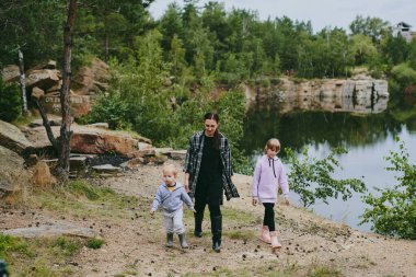 Mutlu bir aile ormanda yürüyüş yapıyor, böğürtlen ve otlar topluyor, patika boyunca seyahat ediyor ve anne ve baba ile çocukları taşlıyor.