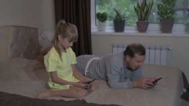 Baba ve kızı evde oturup cep telefonuyla oyun oynuyorlar.