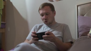 Baba ve kızı evde oturup cep telefonuyla oyun oynuyorlar.