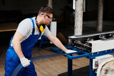 Mavi üniformalı profesyonel mühendis fabrikada çalışıyor. Yuvarlak metal, metal işleme ve metal çit üretimi