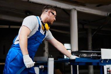 Mavi üniformalı profesyonel mühendis fabrikada çalışıyor. Yuvarlak metal, metal işleme ve metal çit üretimi