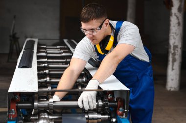 Mavi üniformalı profesyonel mühendis fabrikada çalışıyor. Yuvarlak metal, metal işleme ve metal çit üretimi