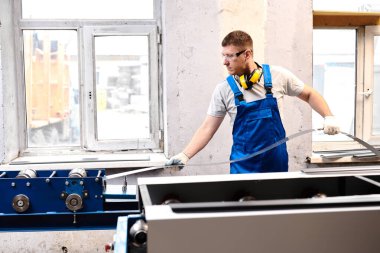 Mavi üniformalı profesyonel mühendis fabrikada çalışıyor. Yuvarlak metal, metal işleme ve metal çit üretimi