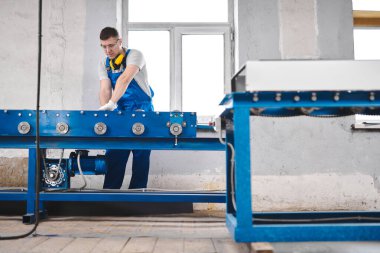 Mavi üniformalı profesyonel mühendis fabrikada çalışıyor. Yuvarlak metal, metal işleme ve metal çit üretimi