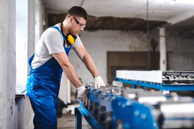 Mavi üniformalı profesyonel mühendis fabrikada çalışıyor. Yuvarlak metal, metal işleme ve metal çit üretimi