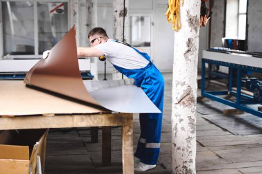 Mavi üniformalı profesyonel mühendis fabrikada çalışıyor. Yuvarlak metal, metal işleme ve metal çit üretimi