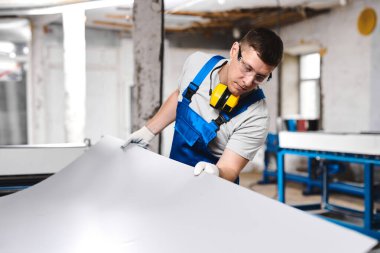 Mavi üniformalı profesyonel mühendis fabrikada çalışıyor. Yuvarlak metal, metal işleme ve metal çit üretimi