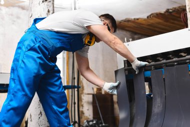 Mavi üniformalı profesyonel mühendis fabrikada çalışıyor. Yuvarlak metal, metal işleme ve metal çit üretimi