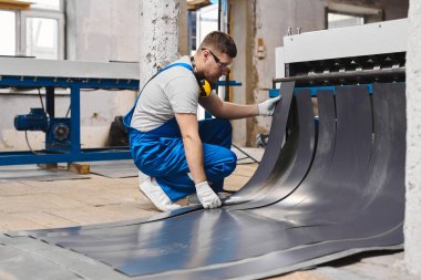 Mavi üniformalı profesyonel mühendis fabrikada çalışıyor. Yuvarlak metal, metal işleme ve metal çit üretimi