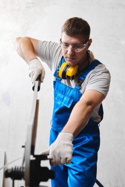 Mavi üniformalı profesyonel mühendis fabrikada çalışıyor. Yuvarlak metal, metal işleme ve metal çit üretimi