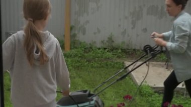 Anne ve kız bahçede çalışıyor, arka bahçedeki bitkilerle ilgileniyor, yatakları hasat ediyor ve yabani otları temizliyor.