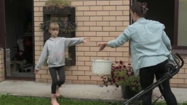 Anne ve kız bahçede çalışıyor, arka bahçedeki bitkilerle ilgileniyor, yatakları hasat ediyor ve yabani otları temizliyor.