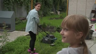 Anne ve kız bahçede çalışıyor, arka bahçedeki bitkilerle ilgileniyor, yatakları hasat ediyor ve yabani otları temizliyor.