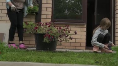 Anne ve kız bahçede çalışıyor, arka bahçedeki bitkilerle ilgileniyor, yatakları hasat ediyor ve yabani otları temizliyor.