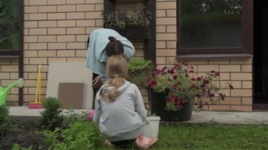 Anne ve kız bahçede çalışıyor, arka bahçedeki bitkilerle ilgileniyor, yatakları hasat ediyor ve yabani otları temizliyor.
