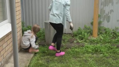 Anne ve kız bahçede çalışıyor, arka bahçedeki bitkilerle ilgileniyor, yatakları hasat ediyor ve yabani otları temizliyor.