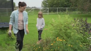 Anne ve kız bahçede çalışıyor, arka bahçedeki bitkilerle ilgileniyor, yatakları hasat ediyor ve yabani otları temizliyor.