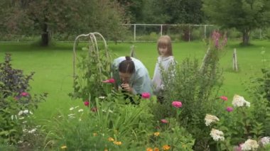 Anne ve kız bahçede çalışıyor, arka bahçedeki bitkilerle ilgileniyor, yatakları hasat ediyor ve yabani otları temizliyor.