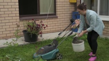 Bahçede çalışan bir kadın, arka bahçedeki bitkilerle ilgilenen, çimleri biçme makinesiyle biçen bir kadın.