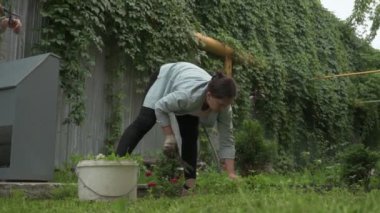 Kadın bahçede çalışıyor, arka bahçedeki bitkilerle ilgileniyor, yatakları hasat ediyor ve yabani otları temizliyor.
