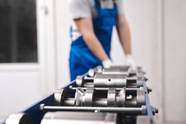 Mavi üniformalı profesyonel mühendis fabrikada çalışıyor. Yuvarlak metal, metal işleme ve metal çit üretimi