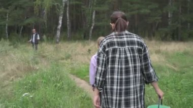Dört kişilik mutlu bir aile ormanda yürür, mantar, böğürtlen ve ot toplar.