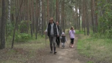 Dört kişilik mutlu bir aile ormanda yürür, mantar, böğürtlen ve ot toplar.