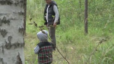 Dört kişilik mutlu bir aile ormanda yürür, mantar, böğürtlen ve ot toplar.