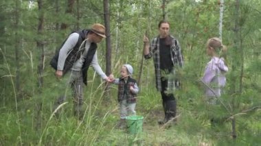 Dört kişilik mutlu bir aile ormanda yürür, mantar, böğürtlen ve ot toplar.
