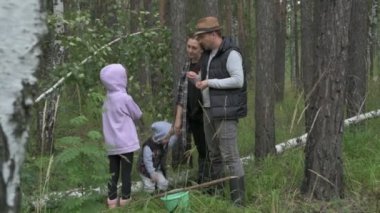 Dört kişilik mutlu bir aile ormanda yürür, mantar, böğürtlen ve ot toplar.