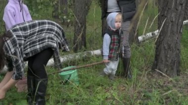 Dört kişilik mutlu bir aile ormanda yürür, mantar, böğürtlen ve ot toplar.