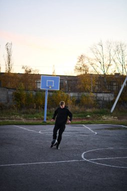 Siyah spor giyimli genç adam spor sahasında futbol oynuyor.