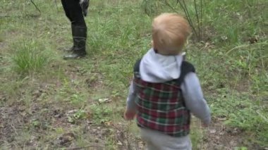 Çocuklu anne ormanda yürüyor, mantar, böğürtlen ve ot topluyor.