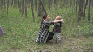 Çocuklu anne ormanda yürüyor, mantar, böğürtlen ve ot topluyor.