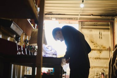 Garajda elektrikli aletlerle çalışan, bir şeyleri tamir eden genç bir adam.