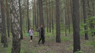 Anne ve kızı yeşil bir ormanda yürürler, mantar ve böğürtlen toplarlar.