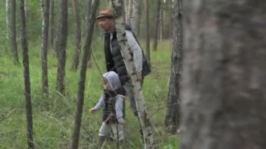 Baba ve oğul yeşil bir ormanda yürürler, mantar ve böğürtlen toplarlar.