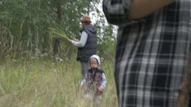 Anne baba ve oğul yeşil ormanda yürürler, mantar ve böğürtlen toplarlar.