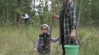 Anne baba ve oğul yeşil ormanda yürürler, mantar ve böğürtlen toplarlar.