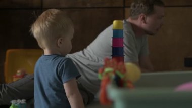 Mutlu aile babası ve küçük oğlu evde birlikte vakit geçirir, oyunlar oynar ve çizgi film izlerler.