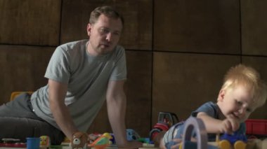 Mutlu aile babası ve küçük oğlu evde birlikte vakit geçirir, oyunlar oynar ve çizgi film izlerler.
