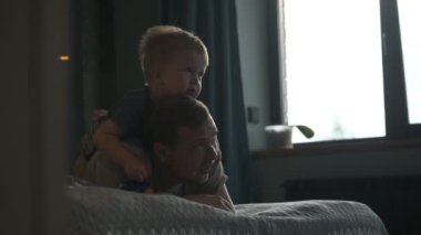 Mutlu aile babası ve küçük oğlu evde birlikte vakit geçirir, oyunlar oynar ve çizgi film izlerler.