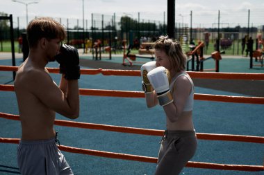 Genç adam ve kadın çift boks antrenmanı, kum torbasına vurmak, spor sahasında spor yapmak.