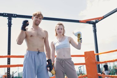 Genç adam ve kadın çift boks antrenmanı, kum torbasına vurmak, spor sahasında spor yapmak.