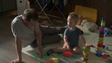 Mutlu aile babası ve küçük oğlu evde birlikte vakit geçirir, oyunlar oynar ve çizgi film izlerler.