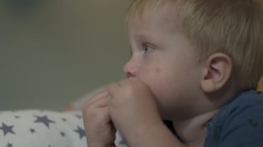 Küçük sarışın çocuk kurabiyeleri yakın mesafeden yer, bebek yer ve televizyon izler.