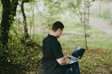 Forest Park 'ta dizüstü bilgisayarla çalışan genç programcının portresi, yazılım geliştiricisi, bilişim teknolojileri.