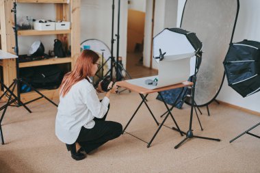 Kadın fotoğrafçı, arka plandaki objelerin fotoğrafını çekiyor. Profesyonel ekipmanlarla birlikte.