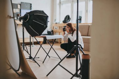 Kadın fotoğrafçı, arka plandaki objelerin fotoğrafını çekiyor. Profesyonel ekipmanlarla birlikte.